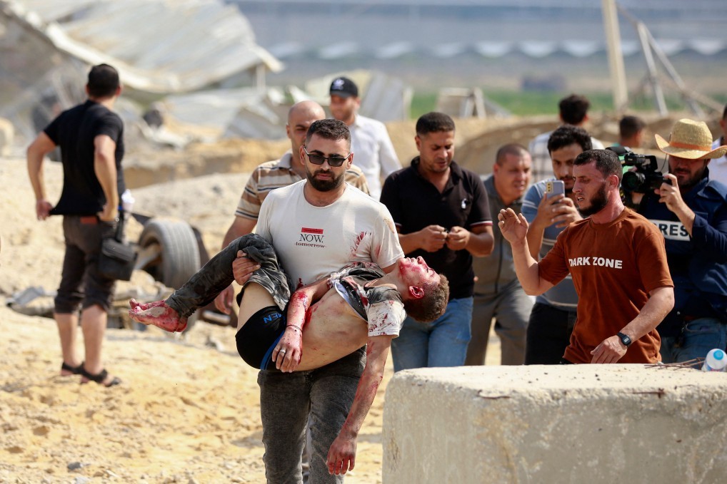 Homem carrega um palestino morto em um ataque aéreo israelense na passagem de Erez – BASHAR TALEB / AFP