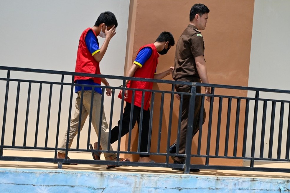 Dois homens indonésios chegam para comparecer à audiência em um tribunal da Sharia — Foto: CHAIDEER MAHYUDDIN / AFP