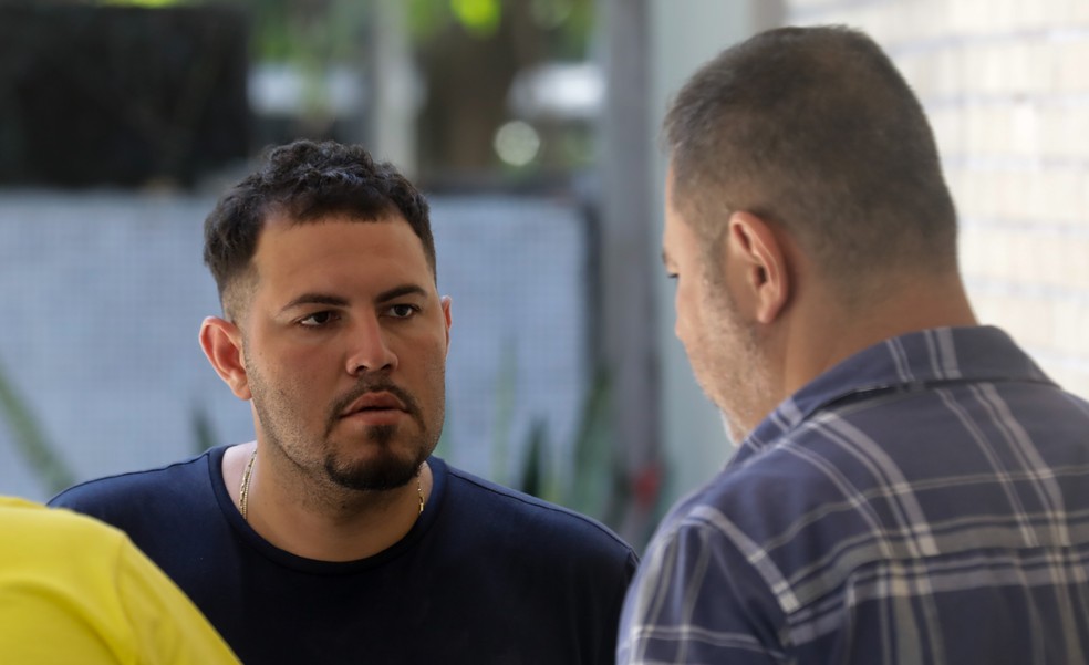 Rafael Rocha (camisa escura) ao ser abordado por um policial na porta do hospital Miguel Couto, onde Benjamim estava internado — Foto: Gabriel de Paiva/Agência o Globo