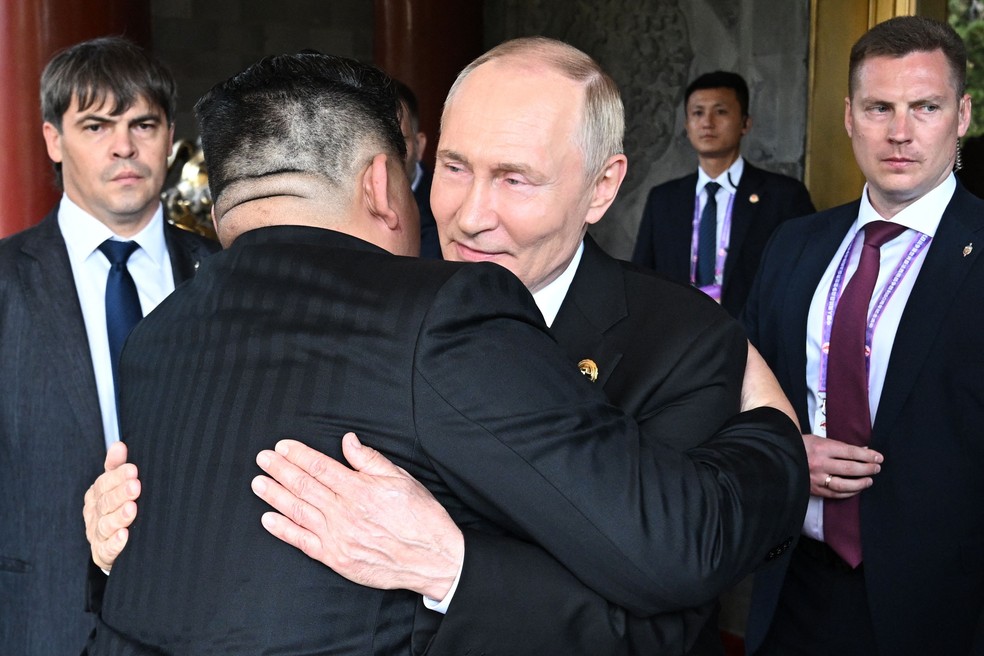 Vladimir Putin e Kim Jong-un se abraçam durante encontro em Pequim — Foto: Sergei Bobylyov/AFP