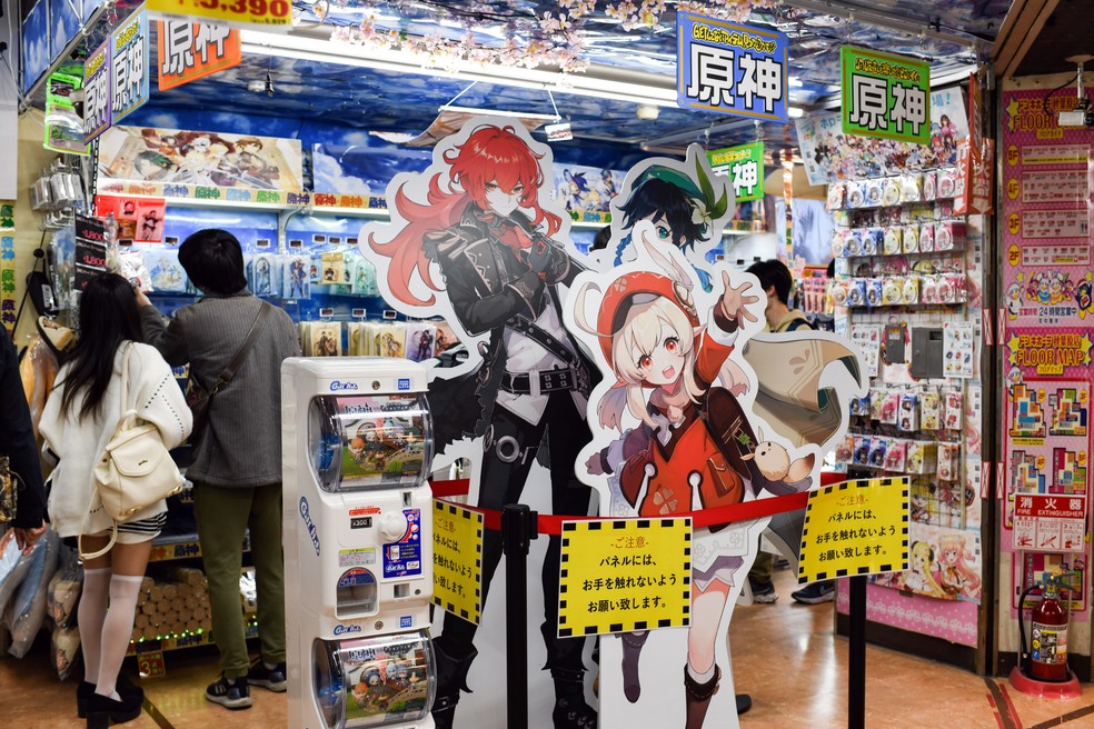 Consumidores olham produtos rrelacionados ao videogame  Genshin Impact em uma loja de Tóquio NYT — Foto:         