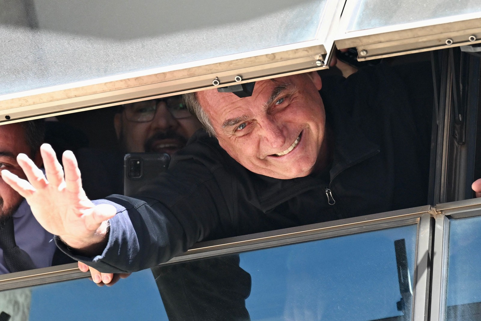 Ex-presidente Bolsonaro cumprimenta apoiadores de uma janela na sede do Partido Liberal em Brasília. Ele retorna depois de 89 dias nos EUA — Foto: Evaristo Sá/AFP