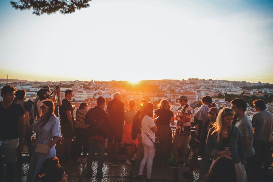 Pessoas aproveitam o fim de tarde com pôr do sol em um dos mirantes de Lisboa