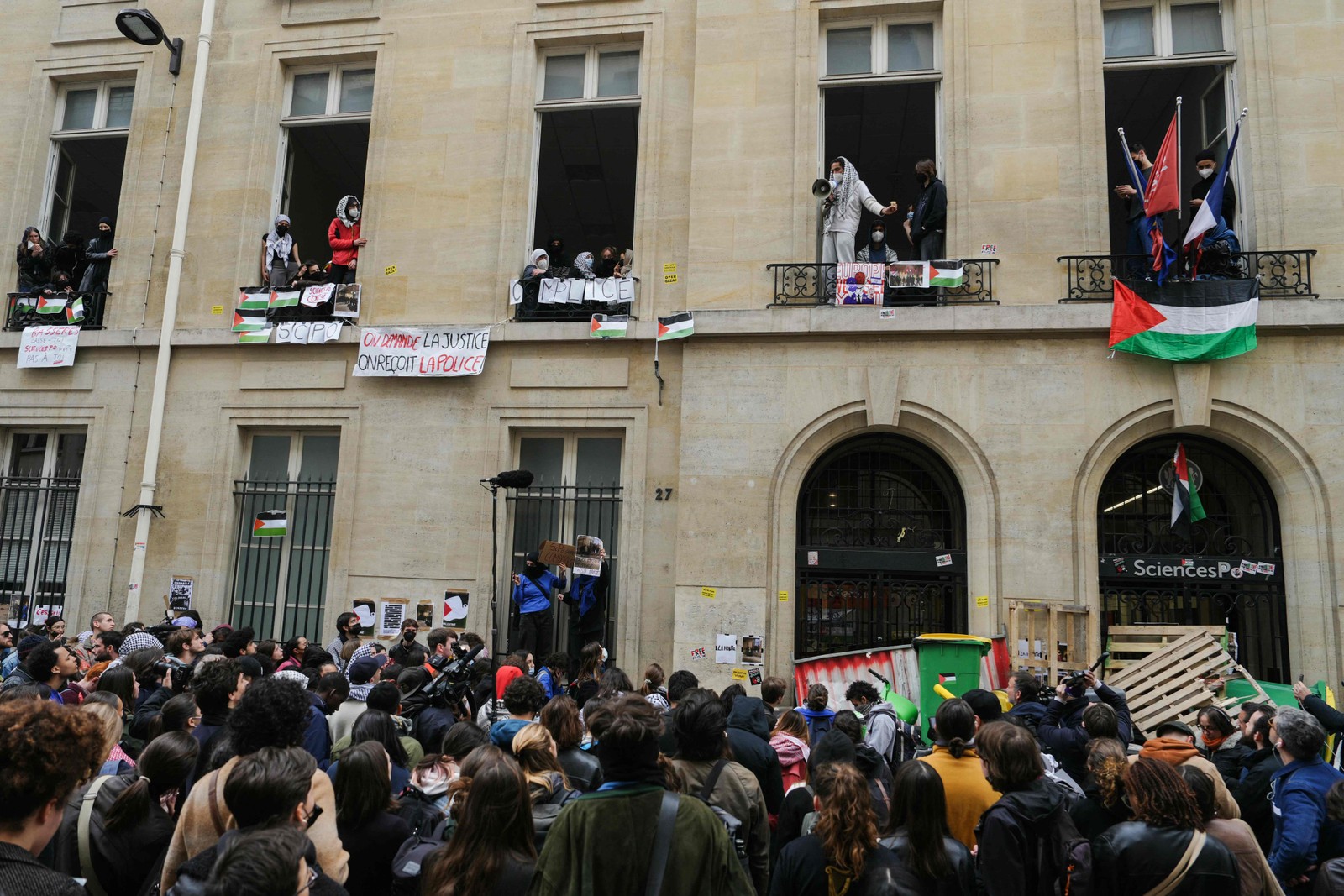 Manifestantes se reúnem em frente ao Instituto de Estudos Políticos (Sciences Po Paris) enquanto estudantes ocupam um prédio, com uma barricada bloqueando a entrada, em apoio aos palestinos, em Paris — Foto: Dimitar DILKOFF / AFP