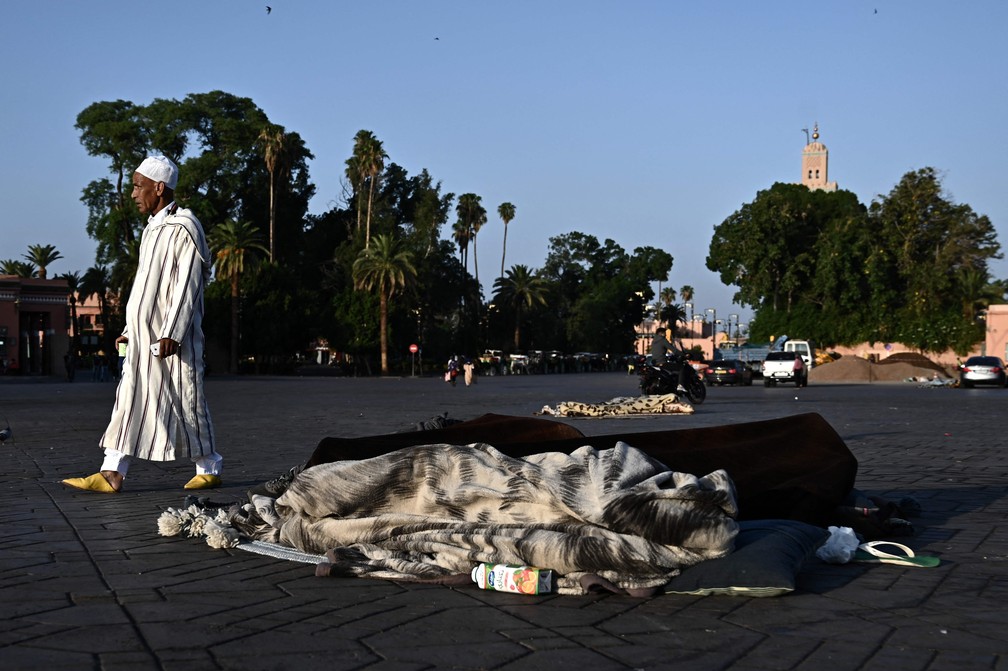 Um homem caminha enquanto pessoas dormem em uma das ruas do bairro antigo de Marrakesh. — Foto: Philippe Lopez/AFP
