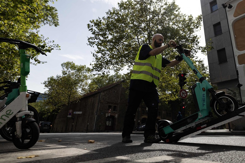 Um funcionário recolhe patinetes elétricos numa rua de Paris: o polêmico meio de transporte está proibido na cidade — Foto: Alain Jocard  / AFP
