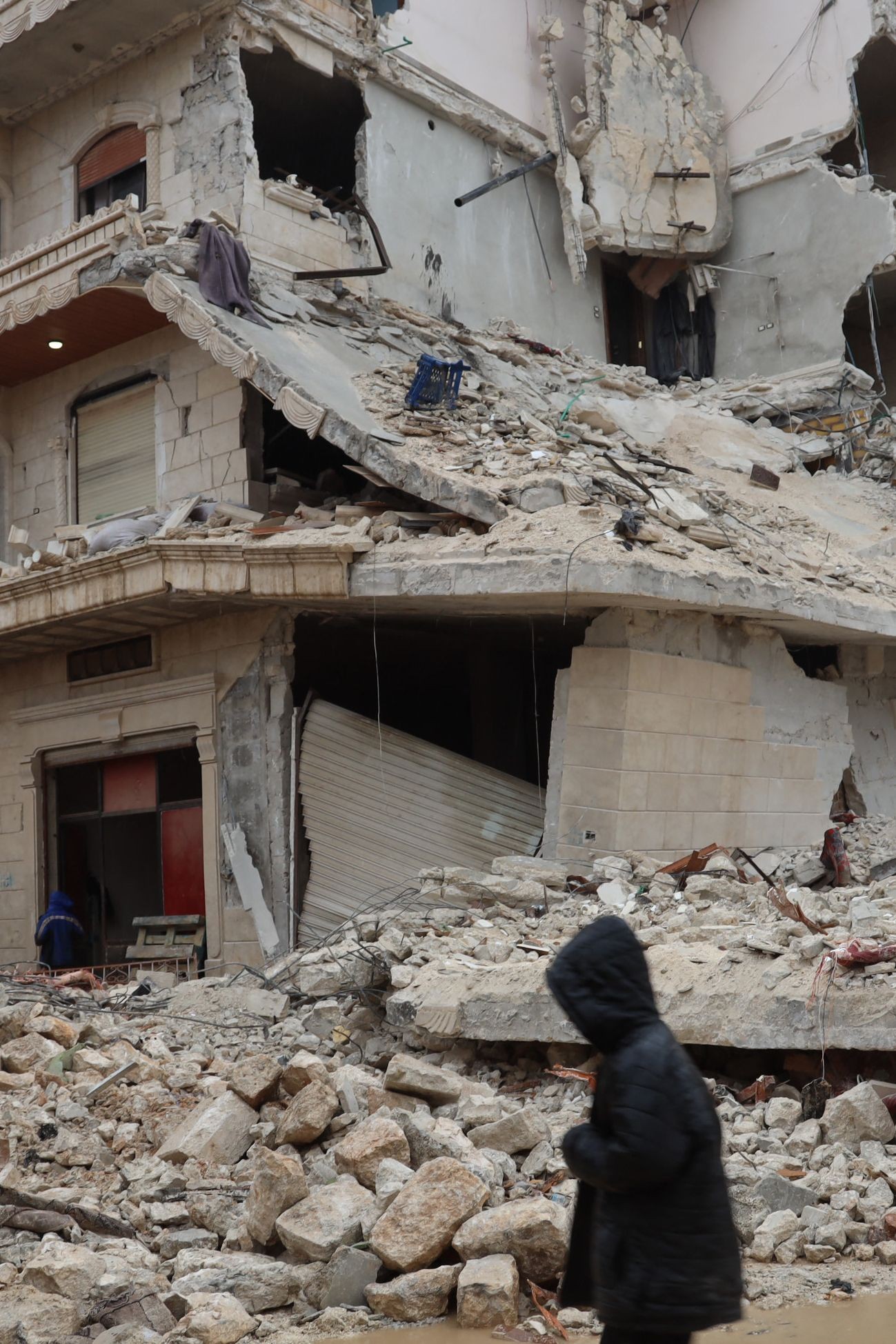 Jovem passa por escombros de prédio após terremoto na cidade de Sarmada, no interior da província de Idlib, no noroeste da Síria, em 6 de fevereiro de 2023 — Foto: Mohammed Al-Rifai / AFP