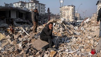 Homem se senta desolado sobre os escombros durante operações de resgate em Hatay, Turquia — Foto: BULENT KILIC/AFP