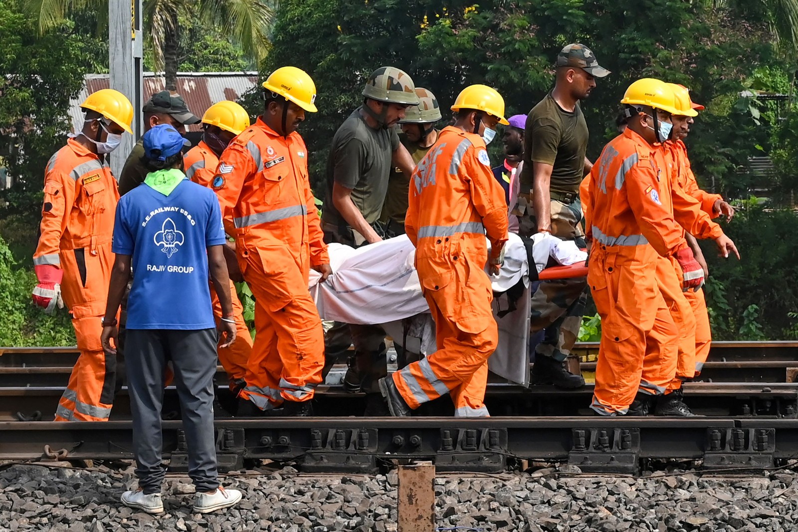 Equipes de resgate carregam o corpo de uma das vítimas ao longo dos trilhos no local do acidente de uma colisão de trens perto de Balasore, a cerca de 200 km da capital do estado, Bhubaneswar — Foto:  Dibyangshu SARKAR / AFP