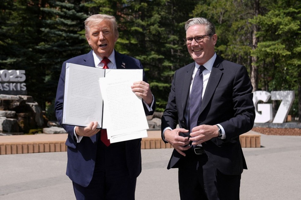 Trump, ao lado do primeiro-ministro britânico Keir Starmer, mostra acordo assinado — Foto: Bloomberg