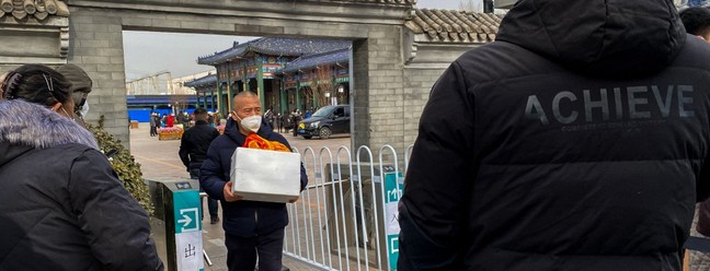 Homem carrega urna com cinzas de parente morto, em Pequim — Foto: Noel Celis / AFP