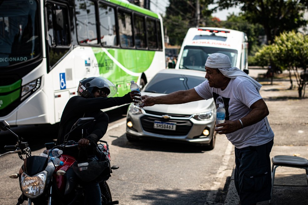 Ivann Monteiro vende água nas ruas da Zona Norte: "Em casa está quente, aqui pelo menos está batendo um ventinho" — Foto: Hermes de Paula