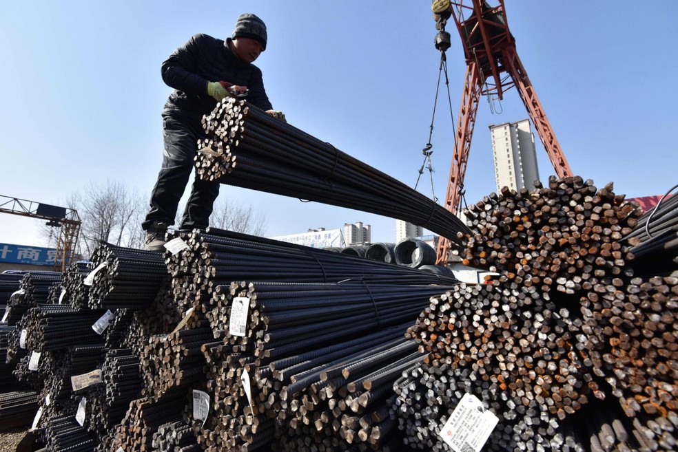 Trabalhadores empilham vergalhões em Fuyang, na China. Maior produtor global de aço, país é o principal alvo de Trump — Foto: AFP