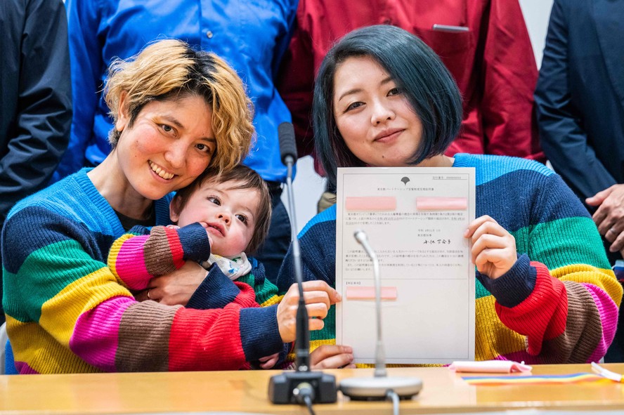 Com o filho no colo, Mamiko Moda (esq) e sua companheira, Satoko Nagamura, exibem o certificado de casamento igualitário em Tóquio