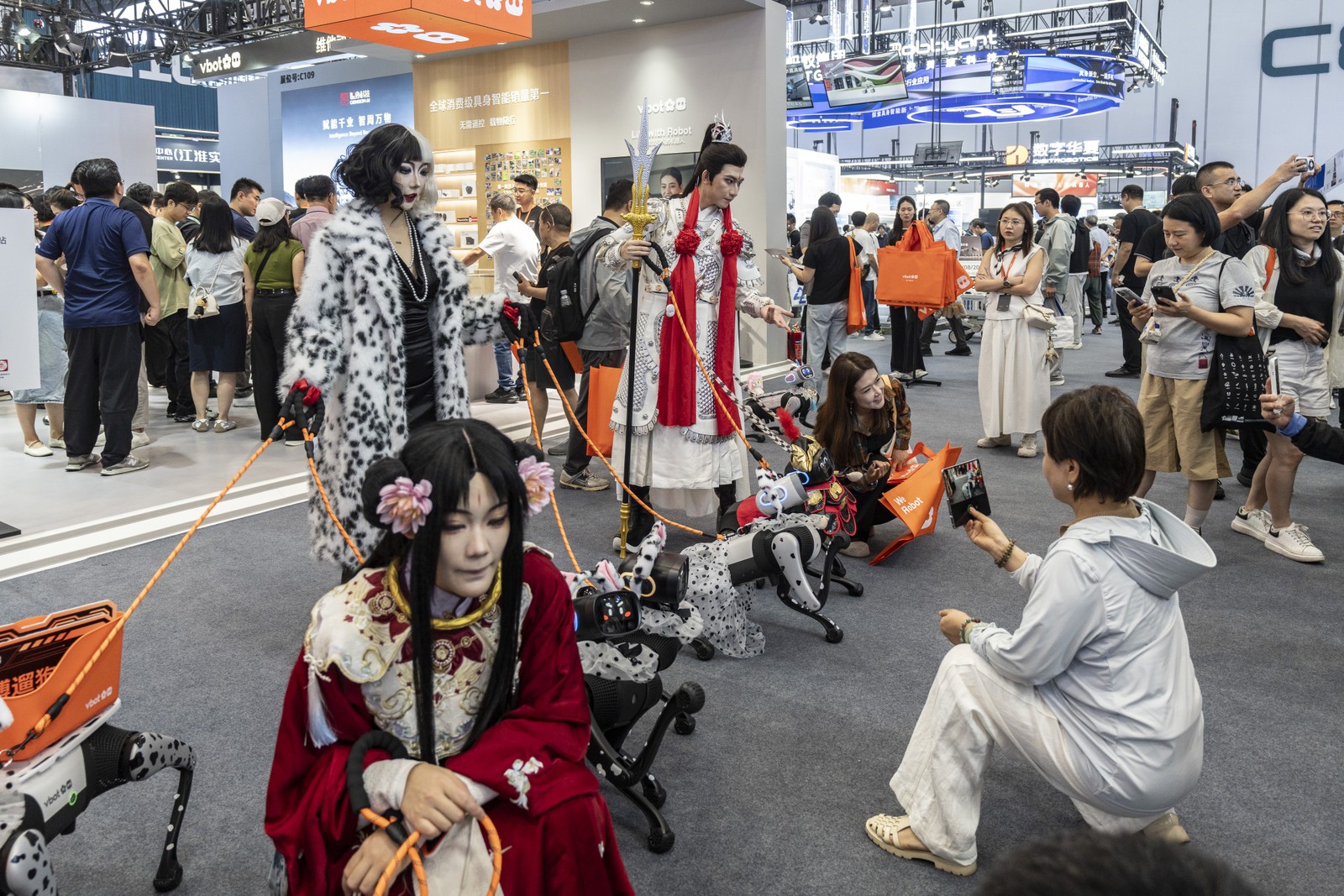 Cruela Cruel e outros personagens s&atilde;o representados por modelos humanoides que posam com c&atilde;es rob&ocirc;s da Vita Dynamics (Vbot) na exposi&ccedil;&atilde;o da Confer&ecirc;ncia Mundial de Rob&oacute;tica em Pequim &mdash; Foto: Qilai Shen/Bloomberg