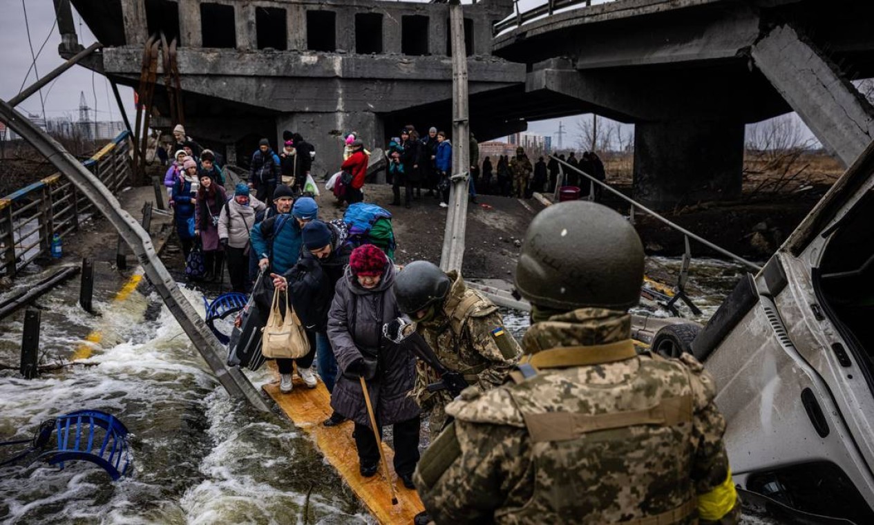 Idosa atravessa ponte destruída em Irpin para fugir da guerra — Foto: DIMITAR DILKOFF / AFP