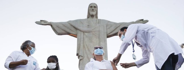 Dulcineia da Silva Lopes, 59 anos, recebe vacina CoronaVac diante da estátua do Cristo Redentor, no Rio de Janeiro. Ela e Therezinha da Conceição, de 80 anos, foram as primeiras moradoras do Rio a receberem a vacina — Foto: Ricardo Moraes / Reuters