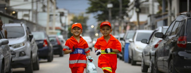 Os irmãos Bryan Mota, de 6 anos, e Bernardo Mota, de 7, ajudam garis a recolherem lixo nas ruas de Bangu — Foto: Lucas Tavares/ O GLOBO