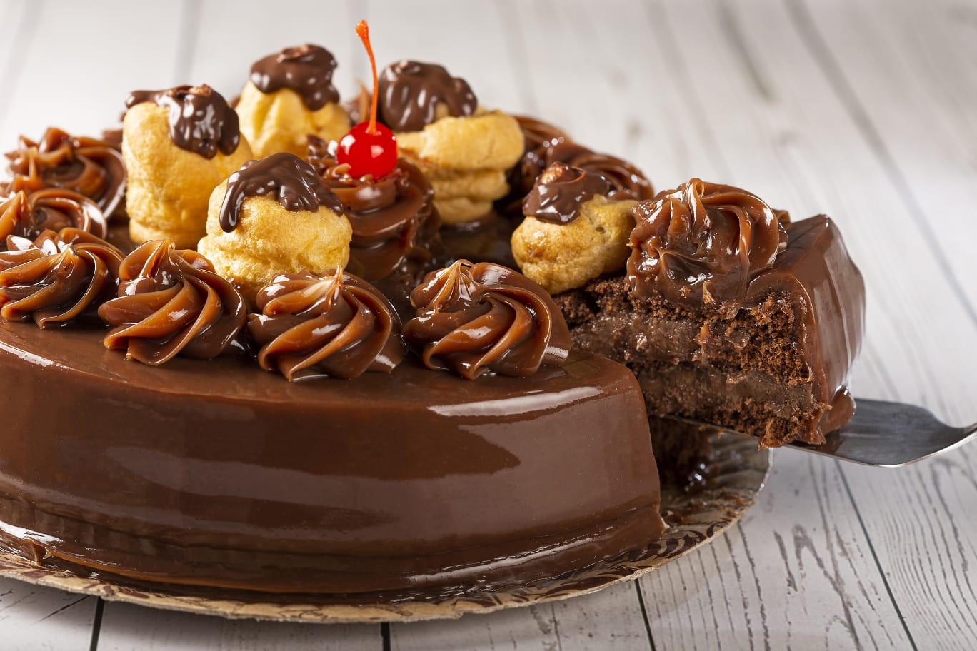 A torta bomba de chocolate da Amantícia (96687-6022) leva massa de pão de ló de chocolate com dois recheios de brigadeiro gourmet, é coberta de brigadeiro negro e finalizada com cereja e profiteroles de brigadeiro negro: R$ 169,90 (média), R$ 129,90 (pequena) e R$ 16,90 (a fatia) — Foto: Divulgação