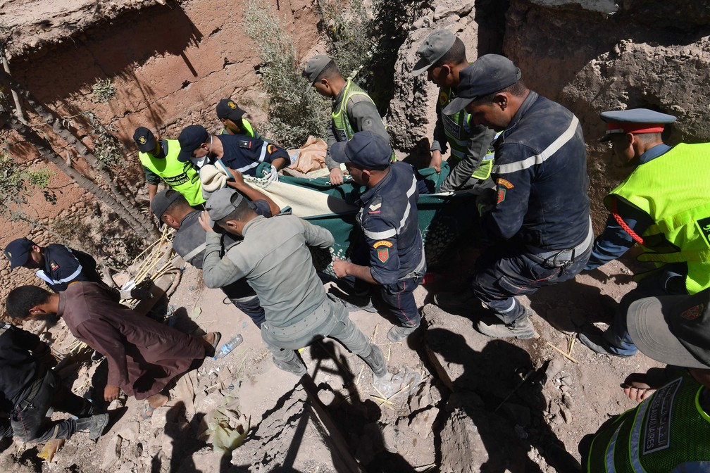 Socorristas retiram um corpo debaixo dos escombros na aldeia de Tiksit, ao Sul de Adassil — Foto: Fethi Belaid/AFP