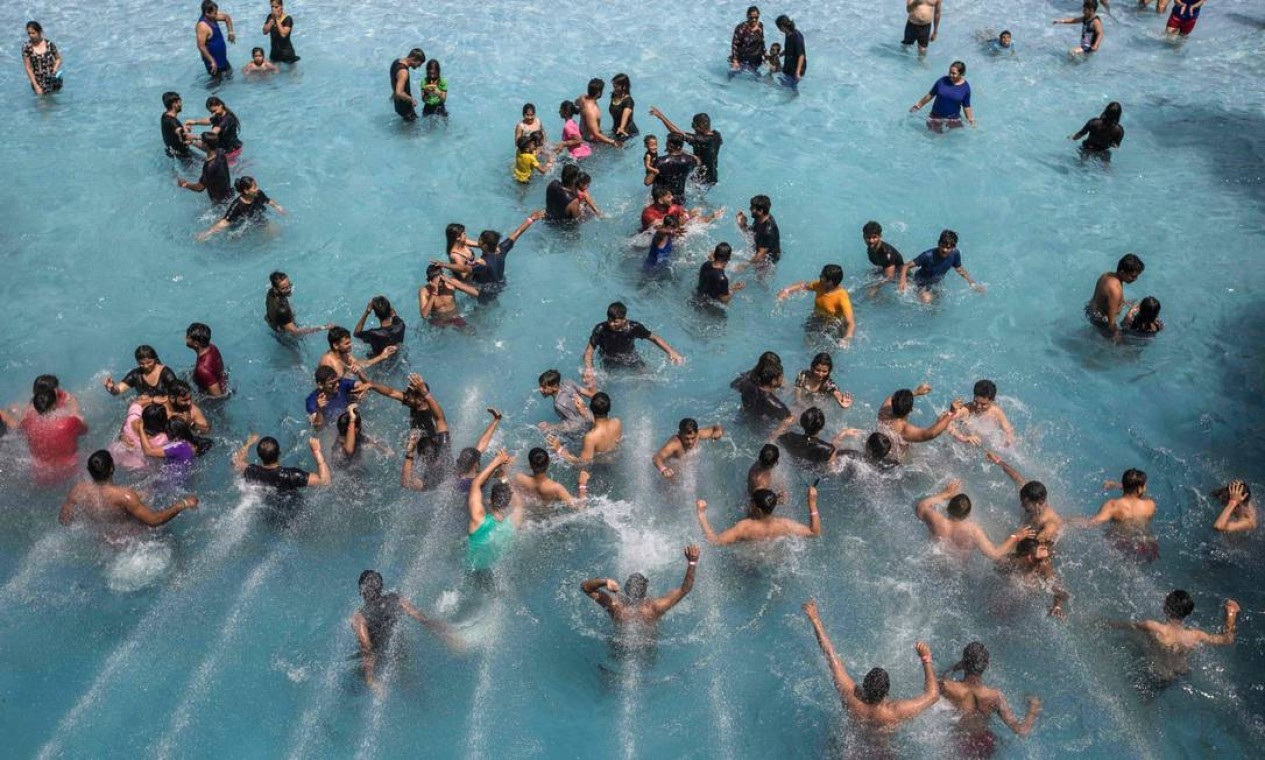Pessoas se refrescam em uma piscina de ondas durante um dia quente de verão em um parque aquático em Nova Delhi  — Foto: XAVIER GALIANA / AFP