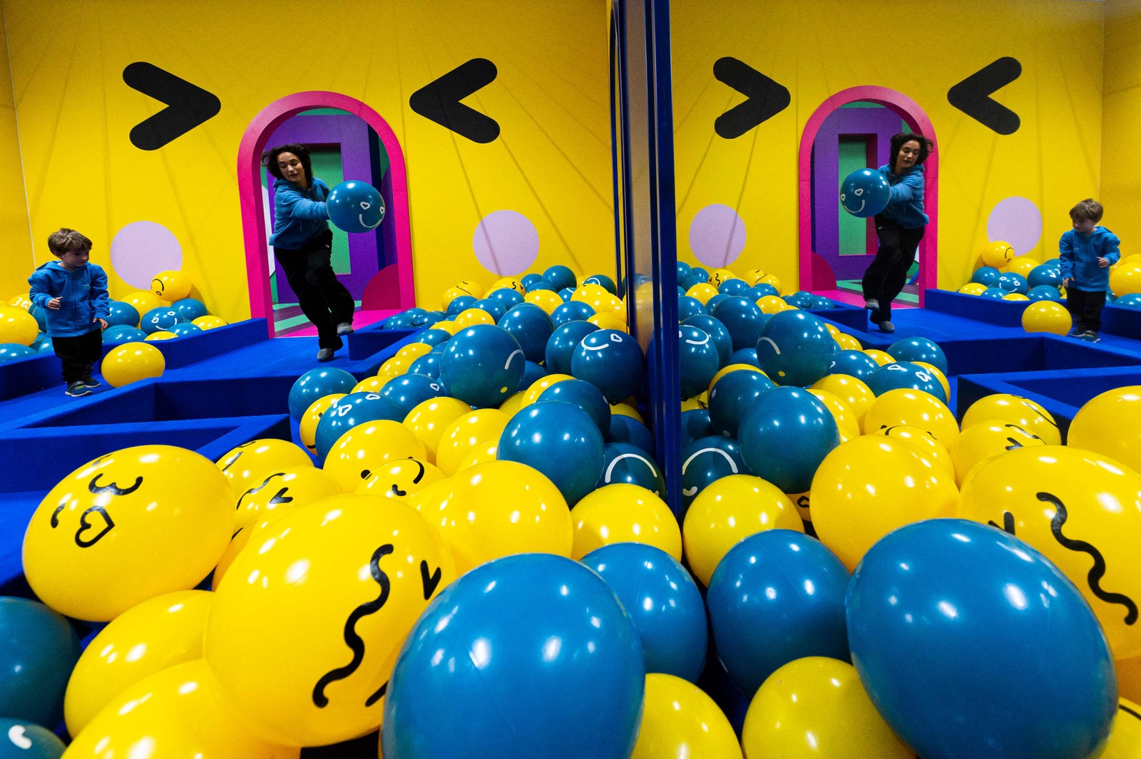 Crianças brincam na "sala emoji", cheia de bolas azuis e amarelas que representam as conhecidas carinhas sorridentesAFP