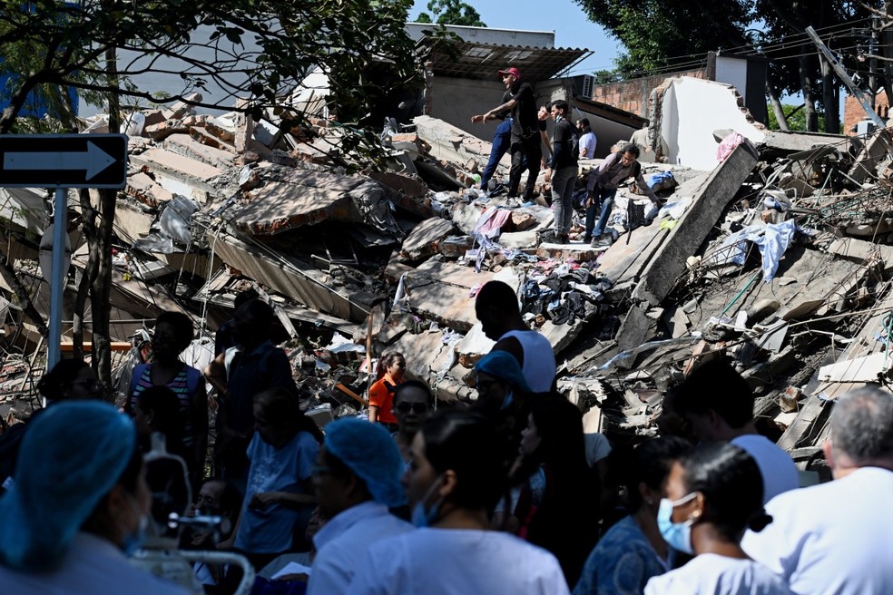 Pessoas procuram por sobreviventes nos escombros de um prédio derrubado pelo terremoto que atingiu o oeste da Colômbia — Foto: JOAQUIN SARMIENTO/AFP