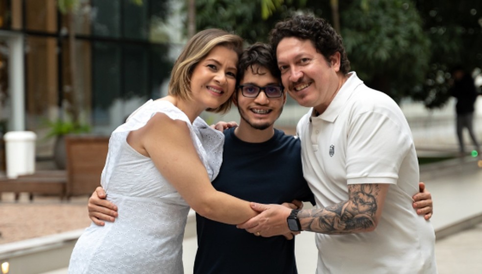 Arthur, hoje aos 19 anos, abraçado por seus seus pais, Ana Paula e Paulo — Foto: Divulgação/Perinatal