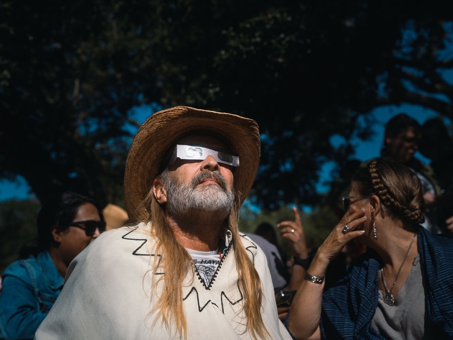 Um espectador usa óculos de visão solar durante um eclipse solar de “anel de fogo” em Driftwood, Texas, em outubro de 2023