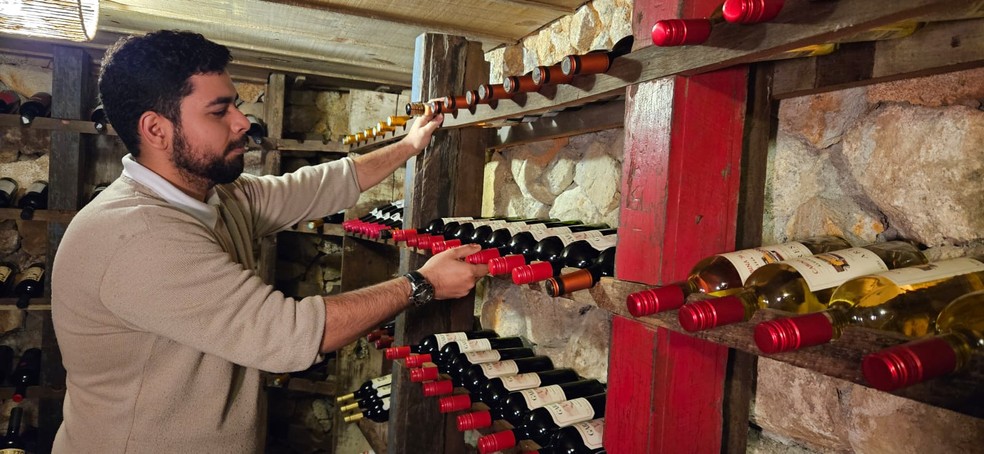 O sommelier Carlos EduardoAlmeida Lima escolhe vinhos na adega — Foto: Cláudia Meneses / Agência O Globo