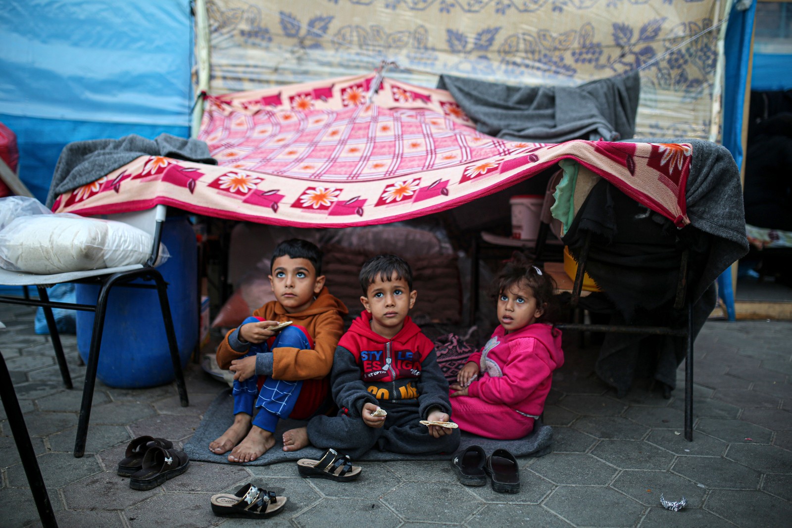 Crianças olham para o céu em um acampamento administrado pelas Nações Unidas para palestinos deslocados em Khan Younis, no sul da Faixa de Gaza — Foto: Yousef Masoud/The New York Times