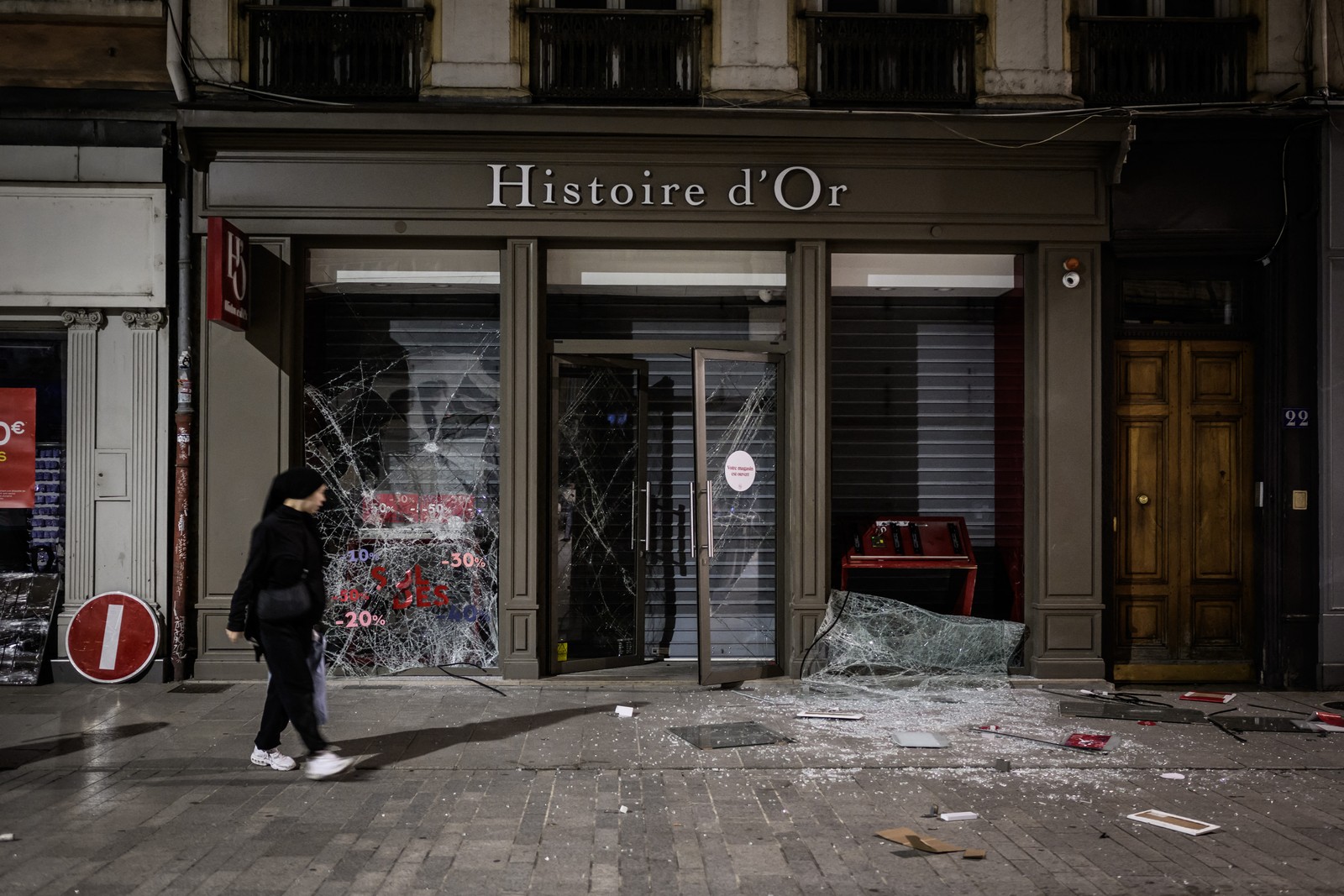 Uma pessoa passa por uma loja saqueada em uma rua de Lyon durante protestos violentos, em 30 de junho de 2023 — Foto: JEFF PACHOUD / AFP