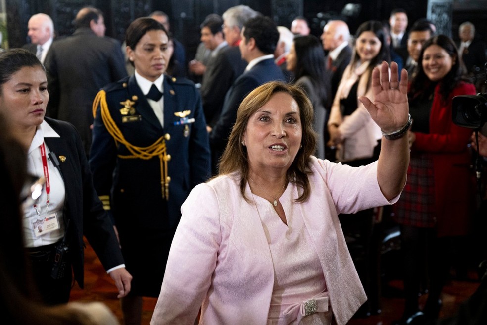 A presidente do Peru, Dina Boluarte, acena para a imprensa após uma cerimônia de promulgação de uma lei de anistia para militares e policiais processados por violações de direitos humanos no Palácio do Governo em Lima, em 13 de agosto de 2025 — Foto: Ernesto BENAVIDES / AFP