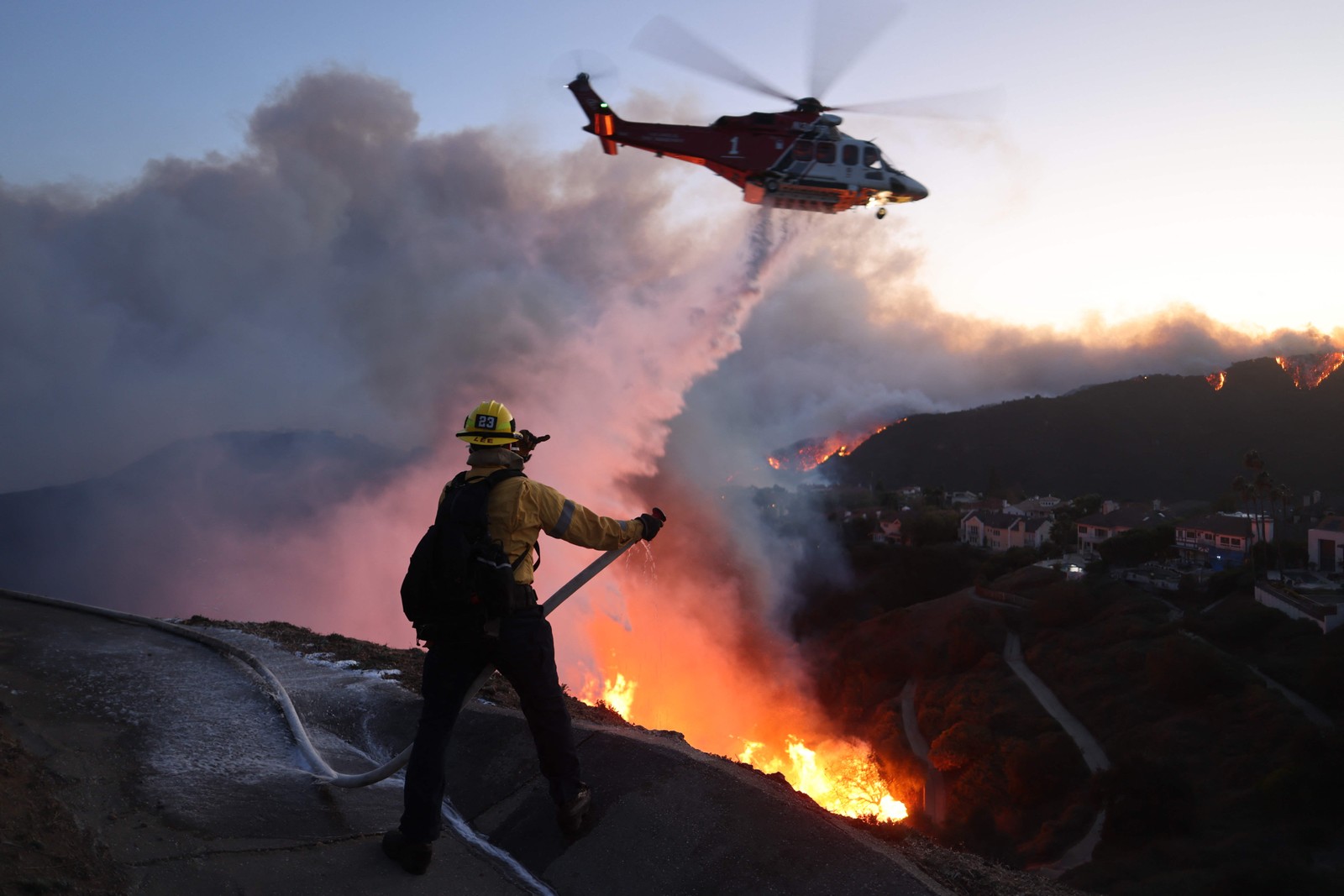 Helicópteros auxiliam bombeiros que estão em terra combatendo o incêndio que cresce na Pacific Palisades — Foto: David Swanson / AFP