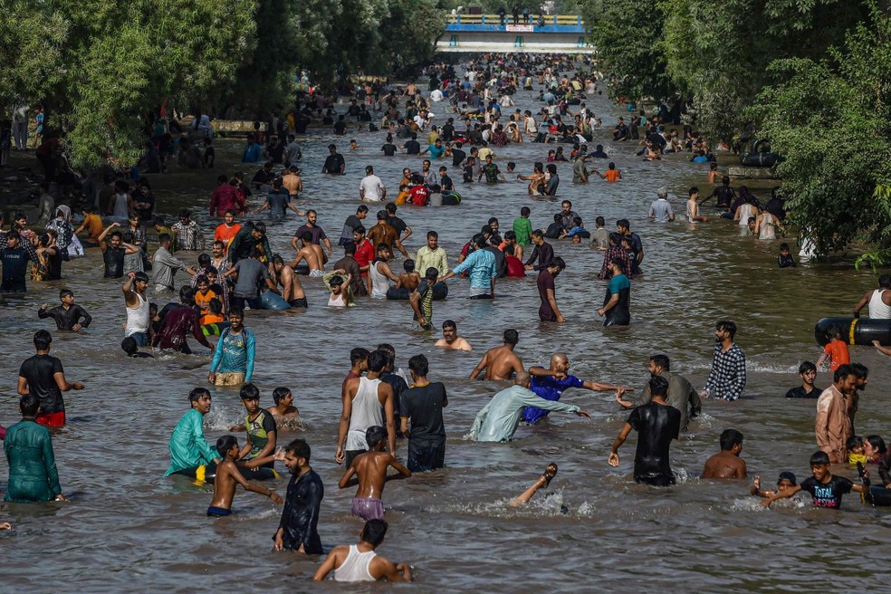 Pessoas se refrescam em rio na cidade de Lahore no Paquistão — Foto: Arif ALI / AFP