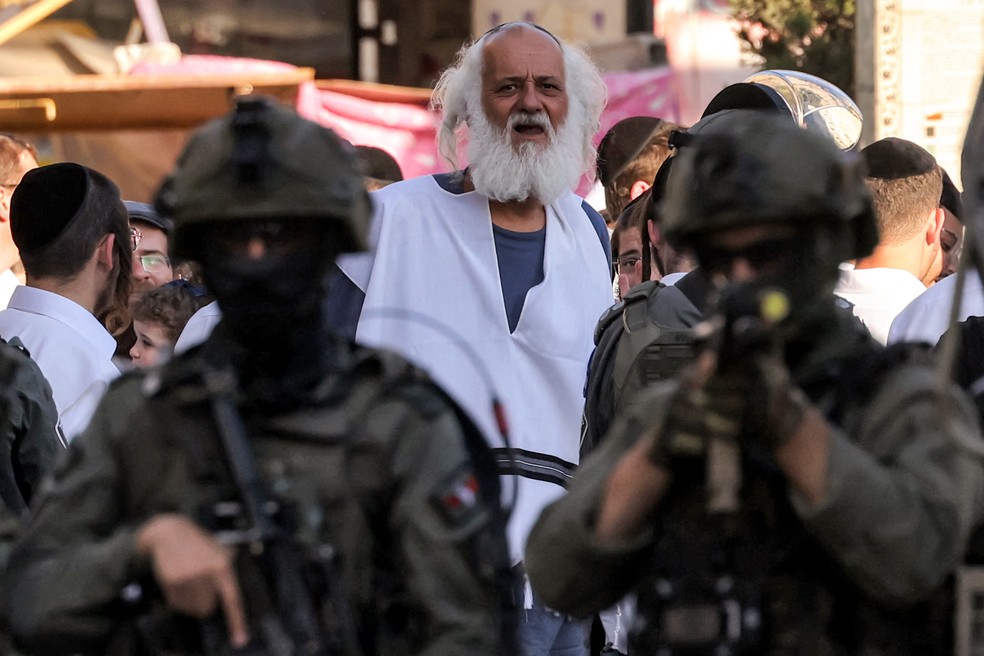 Soldados israelenses montam guarda enquanto colonos israelenses visitam o antigo centro e o mercado da cidade palestina de Hebron, na Cisjordânia ocupada, em 28 de junho — Foto: Hazem Bader/AFP