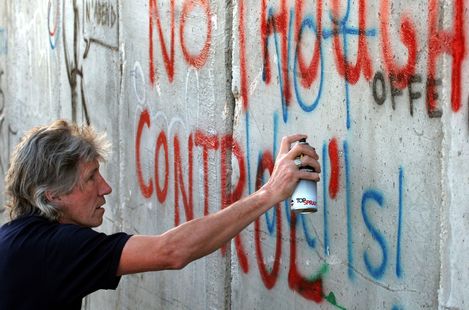 Roger Waters picha as palavras 'Sem controle mental' numa barreira que separa Israel de Belém, em 2006 — Foto: Magnus Johansson/AP