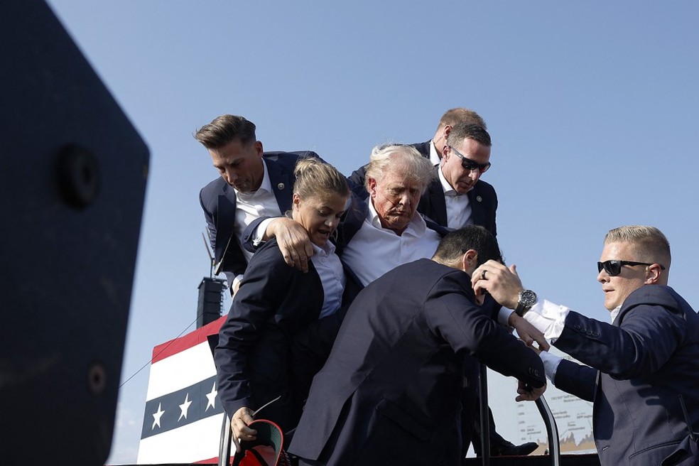 Trump levanta o punho enquanto é retirado do palco durante comícioem Butler, Pensilvânia — Foto: AFP