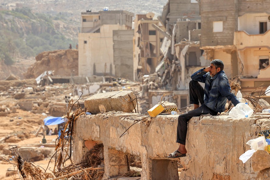 Um sobrevivente sentado nos escombros de um edifício destruído na cidade de Derna, no leste da Líbia