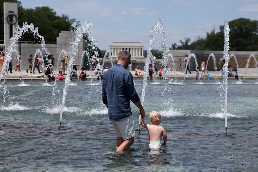 Visitantes e turistas do Memorial da Segunda Guerra Mundial, em Washington, refrescam-se em fonte para escapar do calor escaldante.