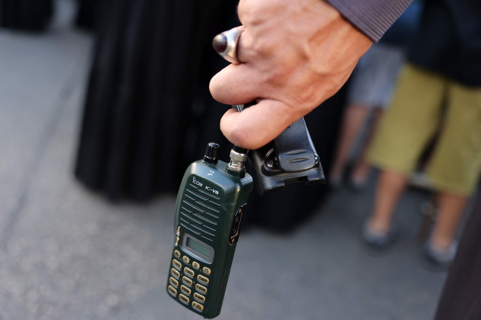 Homem segura walkie-talkie com a bateria removida durante o funeral de pessoas mortas na explosão de pagers, na terça-feira, no Líbano — Foto: ANWAR AMRO / AFP