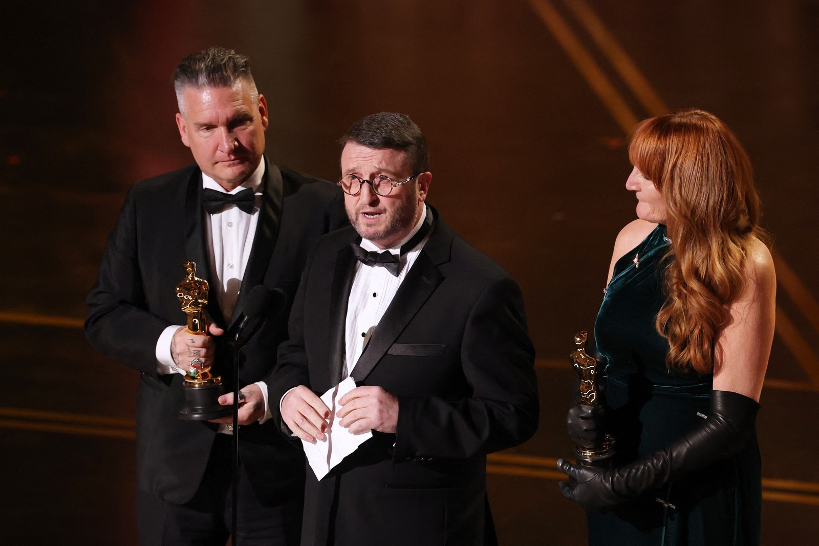 Jordan Samuel, Mike Hill e Cliona Furey recebem o prêmio de Maquiagem e Cabelo por "Frankenstein". — Foto: KEVIN WINTER