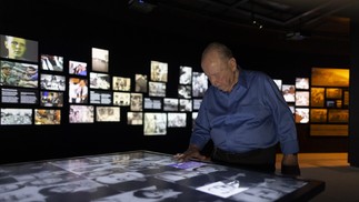 Jorge Tredler, sobrevivente do nazismo que chegou no Brasil ainda criança, observa fotos de outros sobreviventes.  — Foto: Márcia Foletto