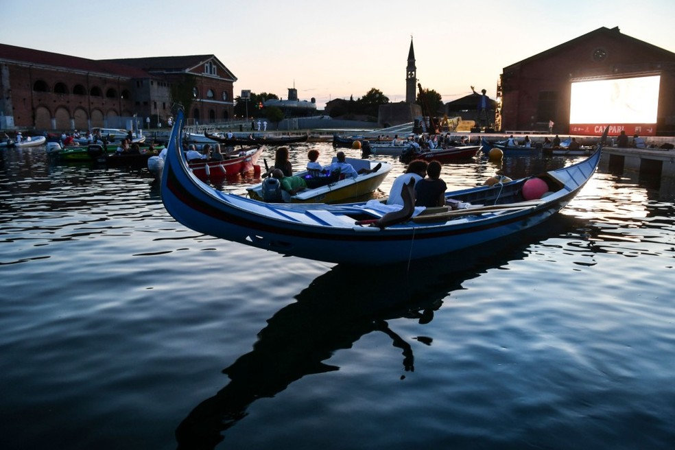 Pessoas observam das gôndolas a exibição do filme "O grande truque", de Christopher Nolan, no primeiro cinema drive-in de Veneza, no Arsenal — Foto: Marco Sabadin/AFP
