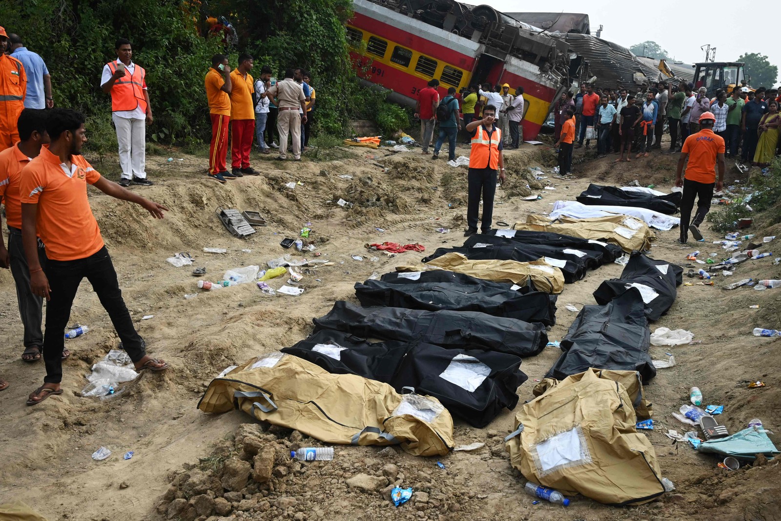 Equipes de resgate e médicos ficam em frente aos corpos das vítimas após uma colisão de trens perto de Balasore, a cerca de 200 km da capital do estado, Bhubaneswar, — Foto: DIBYANGSHU SARKAR / AFP)