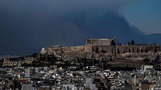 A fumaça sobe atrás do antigo templo do Parthenon no topo da colina da Acrópole enquanto um incêndio florestal se espalha nos arredores de Atenas — Foto: Aris MESSINIS / AFP