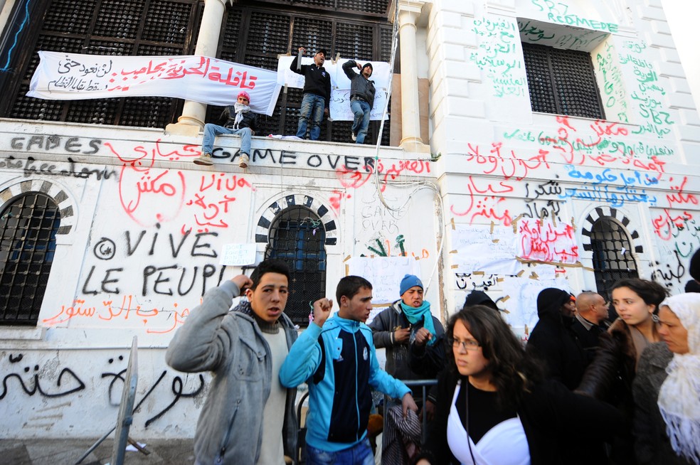 Manifestantes protestam diante do escritório do primeiro-ministro da Tunísia, dias depois da queda do regime do ditador Zine El Abidine Ben Ali, em janeiro de 2011 — Foto: FETHI BELAID / AFP