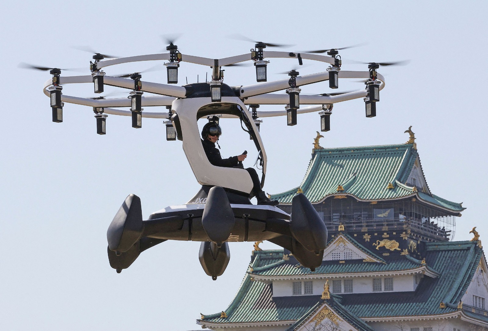 Piloto demonstra uma aeronave fabricada pela LIFT Aircraft, com sede nos EUA, em frente ao Castelo de Osaka, no Japão — Foto: AFP