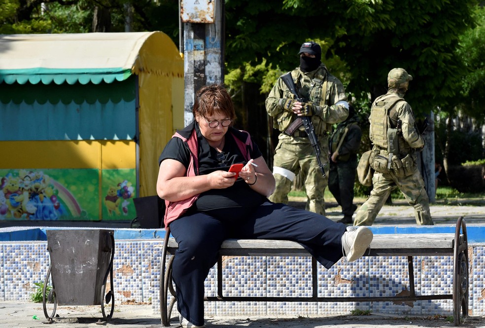 Mulher usa o telefone celular em praça de  Skadovsk, na região ocupada de Kherson — Foto: Olga Matseva/AFP