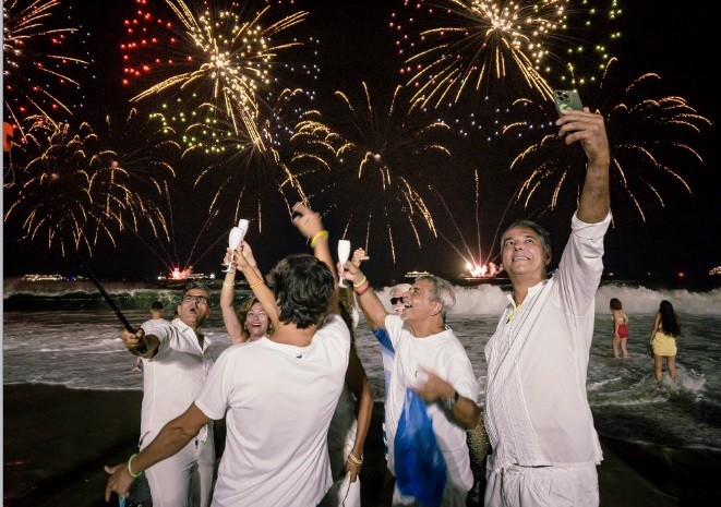 Hora de comemorar a virada com uma selfie, tendo ao fundo a queima de fogos na praia do Leme na hora de brindar a chegada de 2024 — Foto: Léo Martins/Agência O Globo